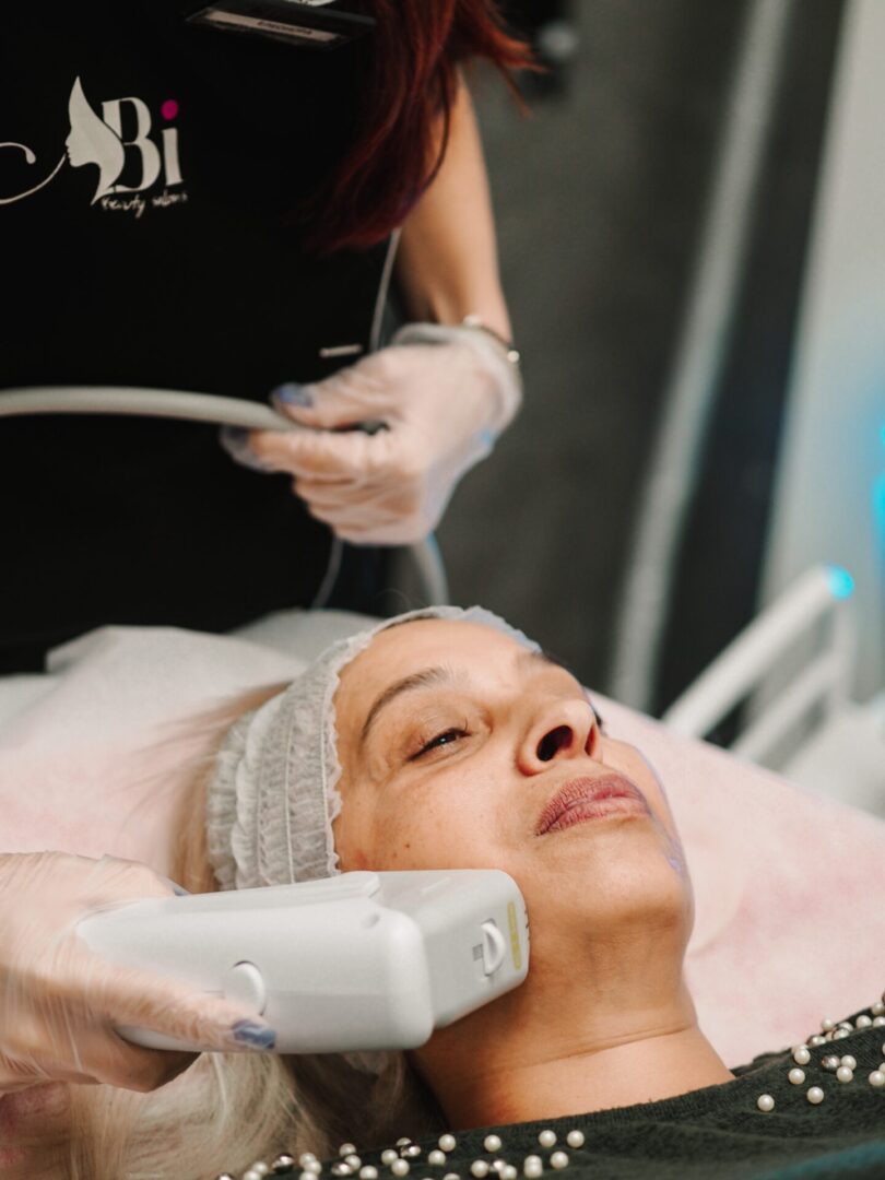 Терапевт на Abi Beauty прилага HIFU накрайник по бузата на клиентка над 50 години